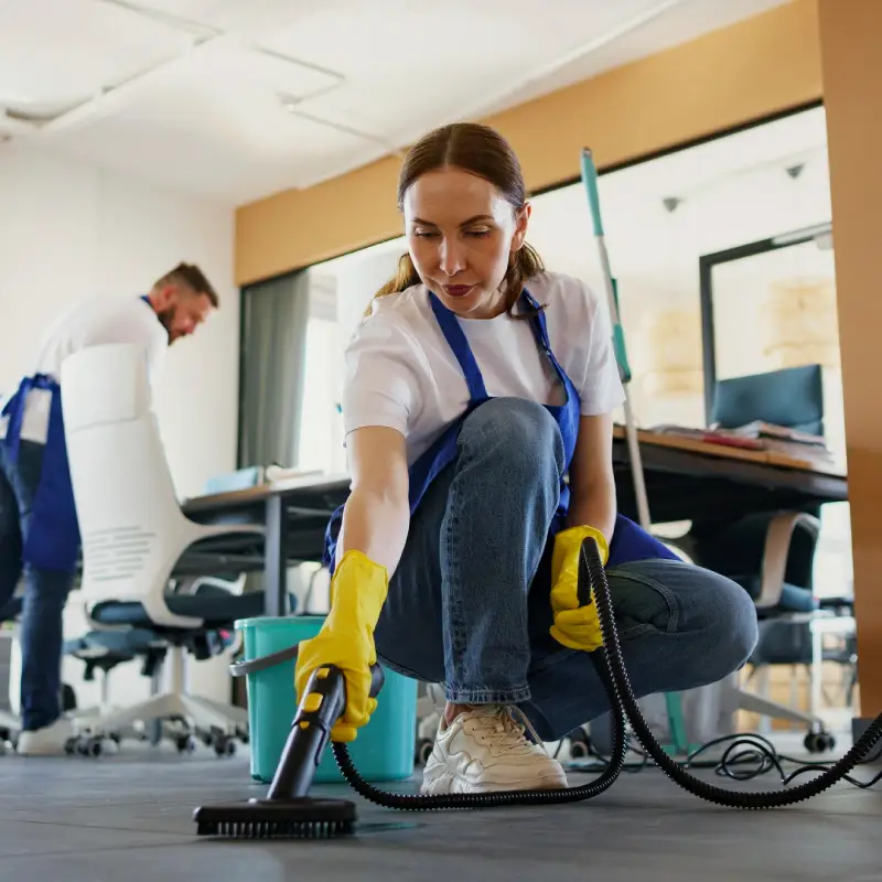 Professional cleaning service person using vacuum cleaner in office